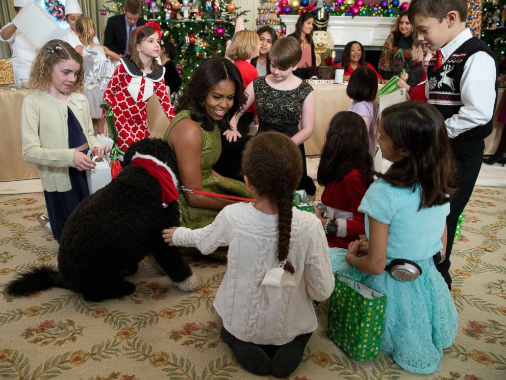 PHOTO: First lady Michelle Obama with dogs Bo, left, and Sunny, behind at right, are surrounded by children in the State Dining Room of the White House in Washington, Dec. 2, 2015.
