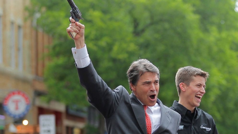 Rick Perry fires a six shooter filled with blanks as NASCAR driver Colin Braun looks on at an event in downtown Fort Worth, Texas on April 15, 2010.