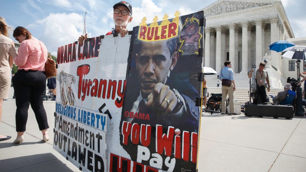 Ronald Brock moves his anti-Obamacare sign as protestors, press, and passersby wait for decisions in the final days of the Supreme Court's term in Washington, D.C. on June 25, 2014.
