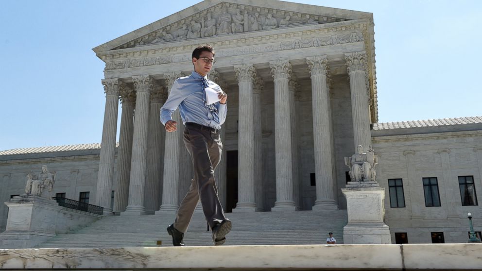 Intern Sam Gringlas runs with one of the Supreme Court rulings in his hand in front of the Supreme Court, June 22, 2015, in Washington.