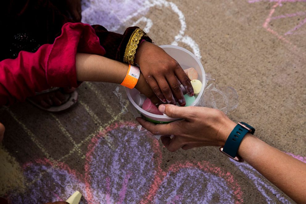 PHOTO: Afghan children take a piece of chalk at a children's activity event held by non-governmental charities at Fort McCoy in Wisconsin, Aug. 31 , 2021.