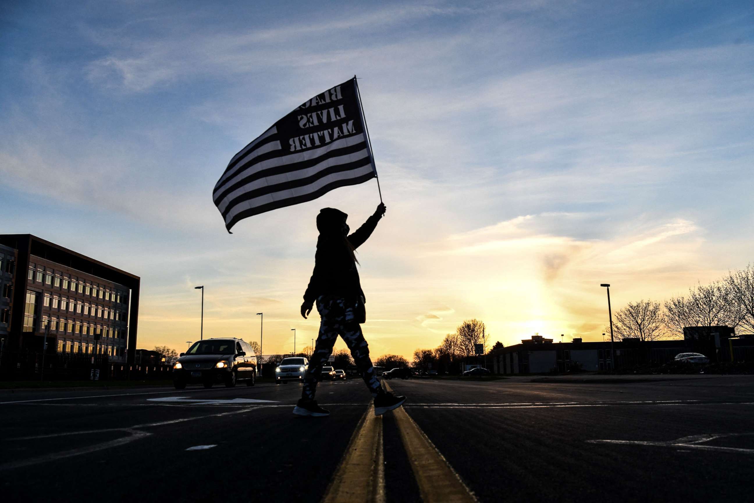 PHOTO: A demonstrator marches, holding a Black Lives Matter flag, during the sixth night of protests over the shooting death of Daunte Wright by a police officer in Brooklyn Center, Minnesota, on April 16, 2021.