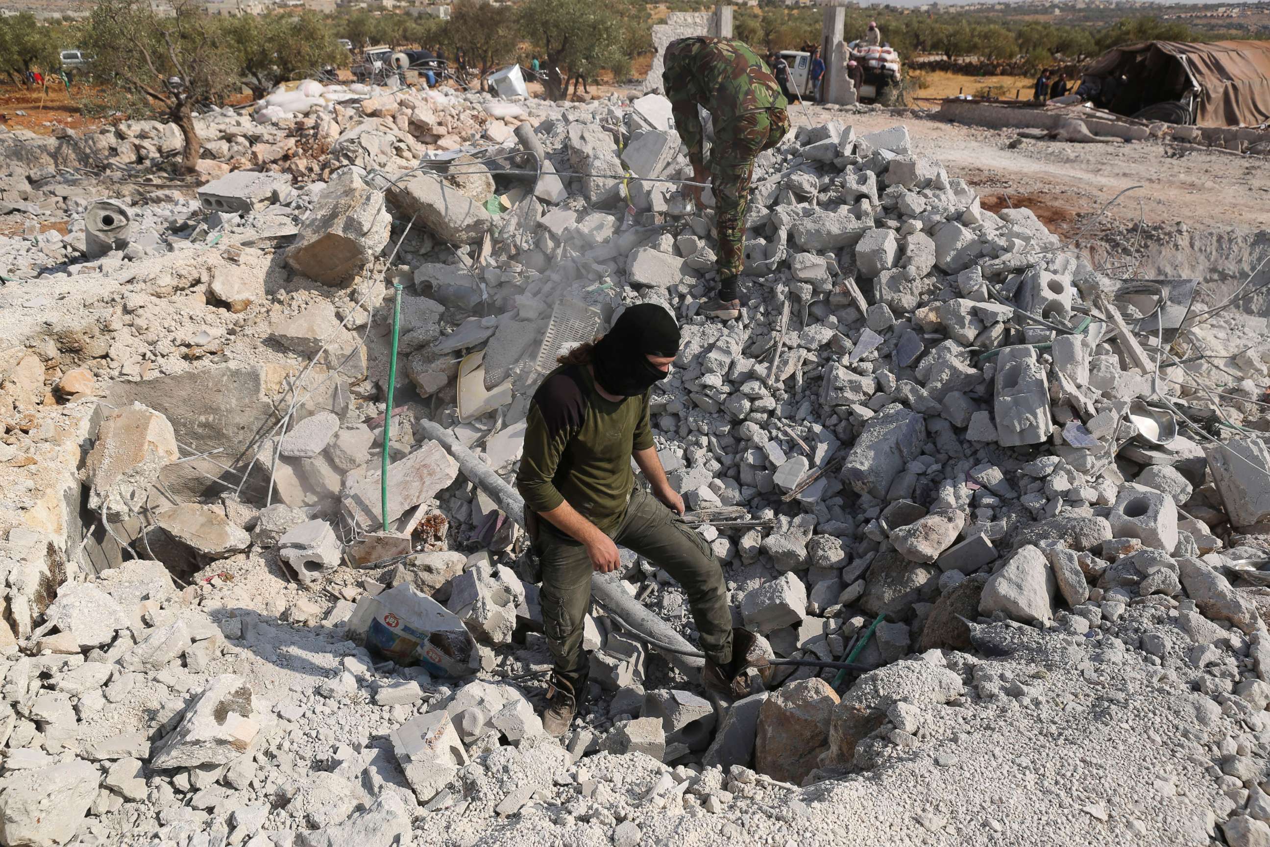 PHOTO: In this Oct. 27, 2019, file photo, people look at a destroyed houses near the village of Barisha, in Idlib province, Syria, after an operation by the U.S. military which targeted Abu Bakr al-Baghdadi.