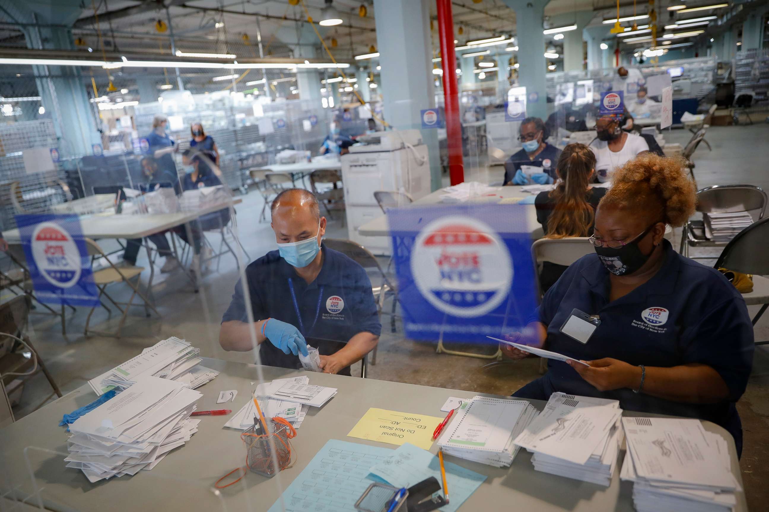 PHOTO: Workers wear personal protective equipment and are separated in pairs from fellow employees by plastic shields as they process ballots at a Board of Elections facility, July 22, 2020, in New York. 