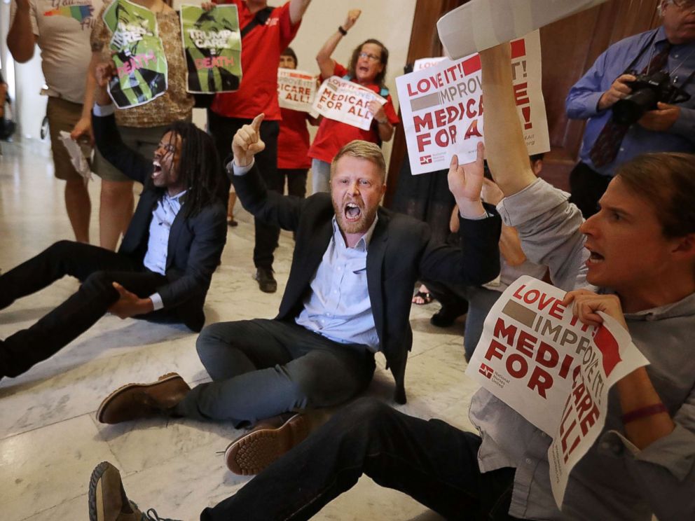 PHOTO: Demonstrators sit on the ground and chant outside the offices of Republican Sen. Ted Cruz while protesting against health care reform legislation in the Russell Senate Office Building on Capitol Hill on July 10, 2017, Washington.