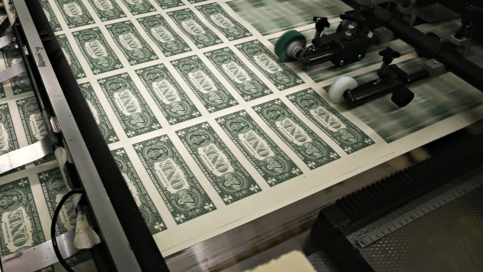 Sheets of one dollar bills run through the printing press at the Bureau of Engraving and Printing, March 24, 2015, in Washington, DC. 