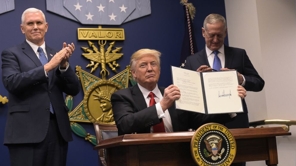 President Donald Trump shows his signature on executive orders alongside Defense Secretary James Mattis and Vice President Mike Pence, Jan. 27, 2016, at the Pentagon in Washington.
