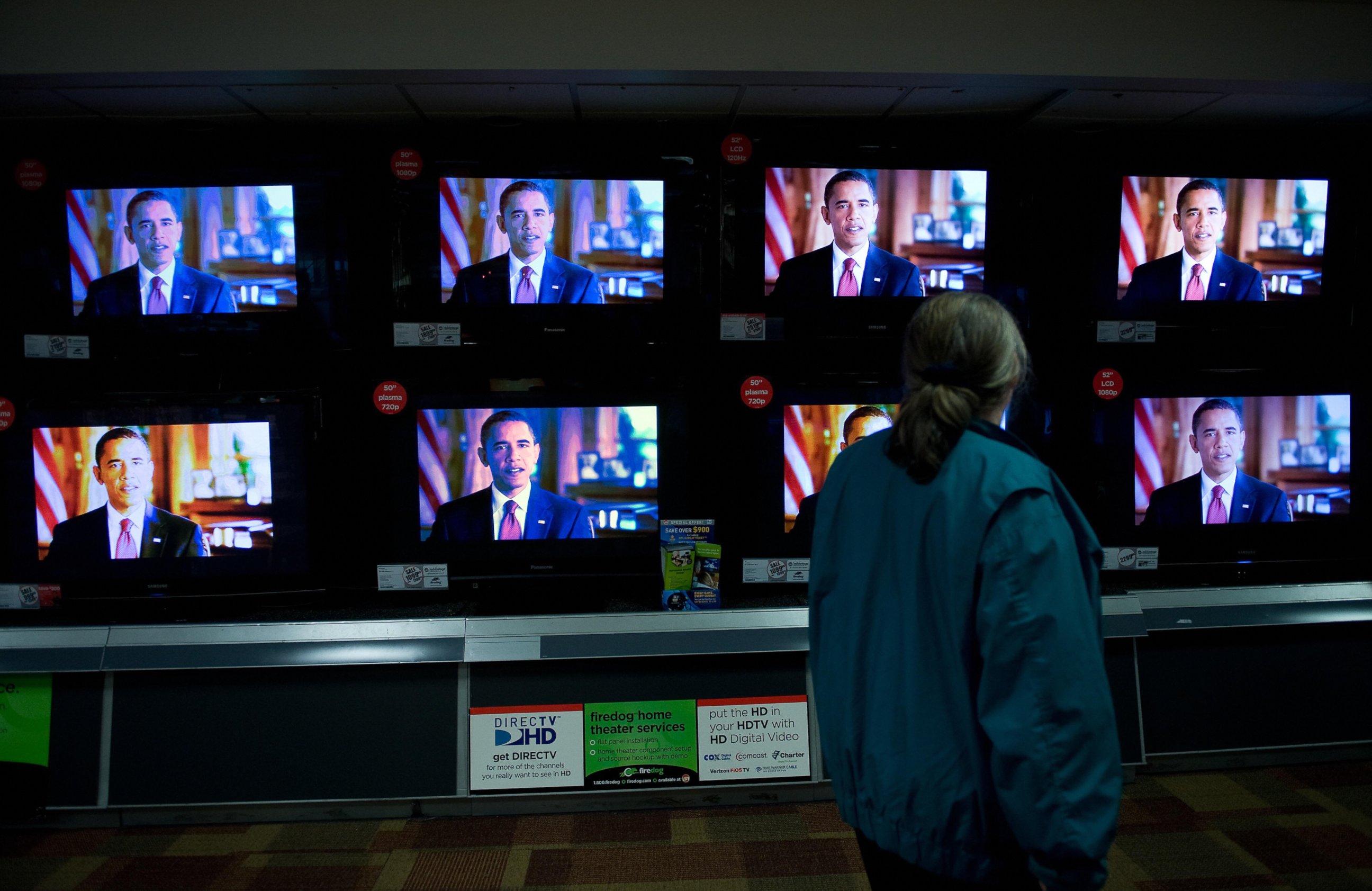 PHOTO: A woman watches Barack Obama on television screens at an electronics shop in Wheaton, Maryland, Oct. 29, 2008, as he speaks during a 30-minute prime-time infomercial on all major networks. 