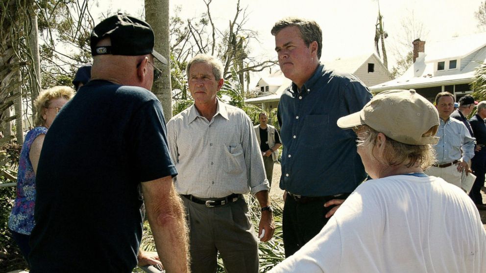 PHOTO: U.S. President George W. Bush (L) and his brother Florida Governor Jeb Bush (R) talk to local residents while touring the damage left by Hurricane Charley in Punta Gorda, Florida, on Aug. 15, 2004. 