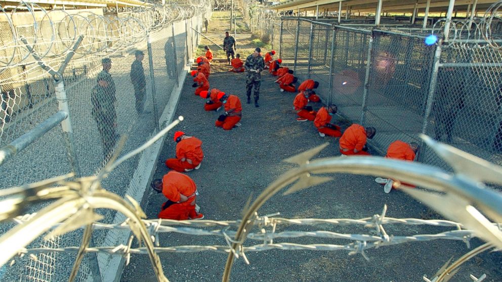 In a photo provided by the U.S. Navy, U.S. Military Police guard Taliban and al Qaeda detainees on Jan. 11, 2002 in a holding area at Camp X-Ray at Naval Base Guantanamo Bay, Cuba during in-processing to the temporary detention facility. 
