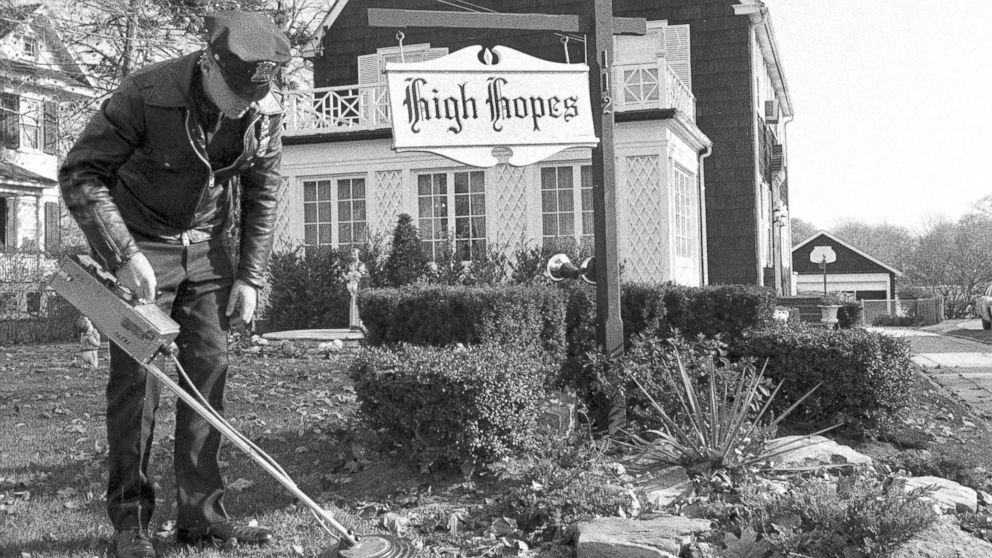 PHOTO: Suffolk County policeman uses mine detector as he sweeps through dead leaves on lawn of Ronald DeFeo's 12-room, $75,000 Dutch colonial home in Amityville.