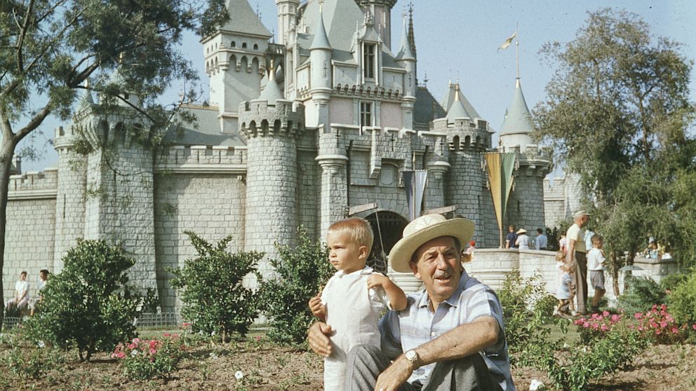Walt Disney (1901-1966) sits on a grassy lawn with his grandson, in front of the Magic Kingdom's castle at Disneyland, Anaheim, Calif., circa 1955.  