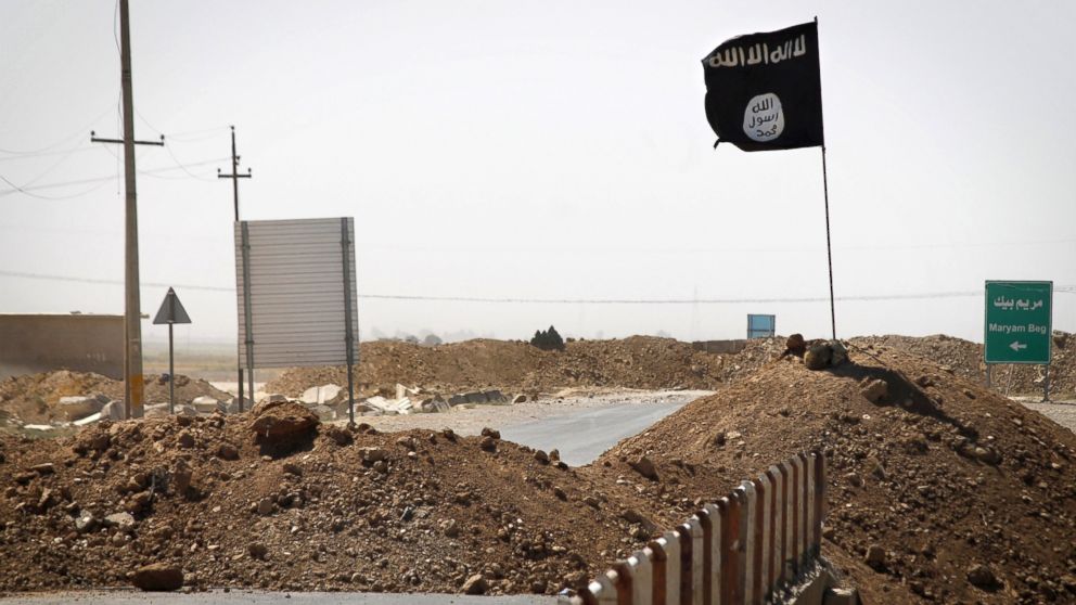 A flag of the Islamic State is seen on the other side of a bridge at the front line of fighting between Kurdish Peshmerga fighters and Islamist militants in Rashad, on the road between Kirkuk and Tikrit, Sept. 11, 2014.