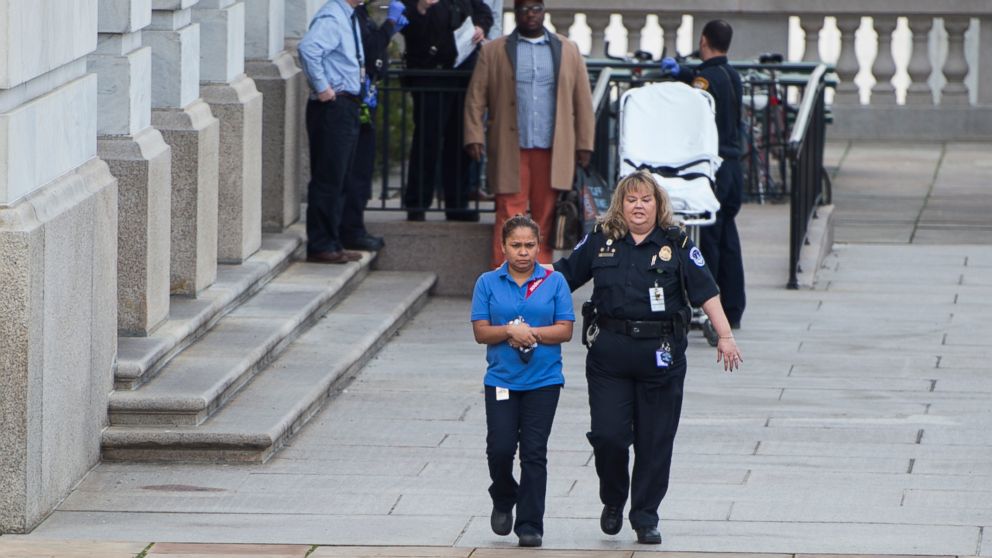 A U.S. Capitol Police officer escorts a Sodexo worker from the Longworth House Office Building after an apparent construction accident left some people in the Longworth cafeteria feeling sick on Jan. 15, 2016.