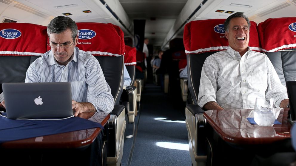 Then Republican presidential candidate Mitt Romney, right, laughs as his senior adviser and spokesman, Kevin Madden, works on his laptop on his campaign plane, Oct. 29, 2012, en route to Moline, Ill.