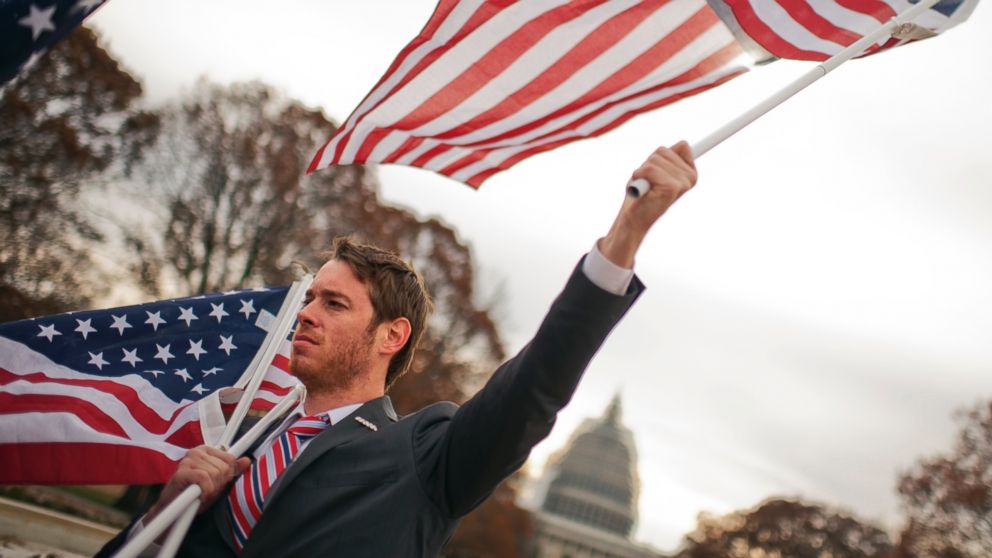 Montana Martin, a Marine veteran from West Virginia that served in Iraq, holds flags during a rally held by the Iraq and Afghanistan Veterans of America in Upper Senate Park in Washington, Dec. 4, 2014. 
