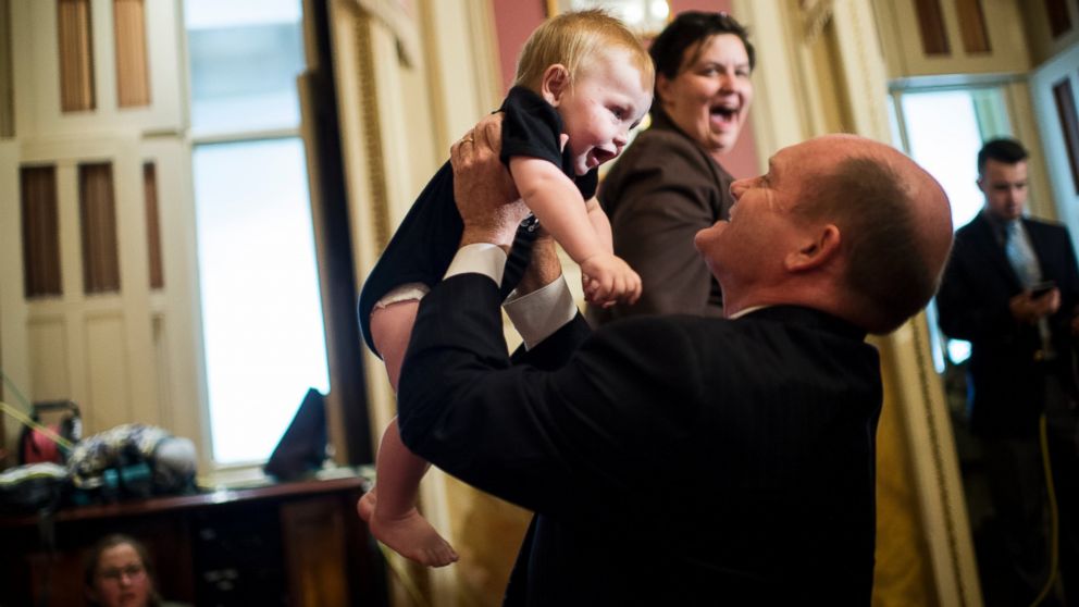 Sen. Chris Coons plays with 7-month-old Max Huijbregts of Washington before the start of the Senate Democrats' news conference in the Capitol, May 25, 2016, to demand that the full Congress immediately pass emergency funding to combat the spread of the Zika virus in the United States. 