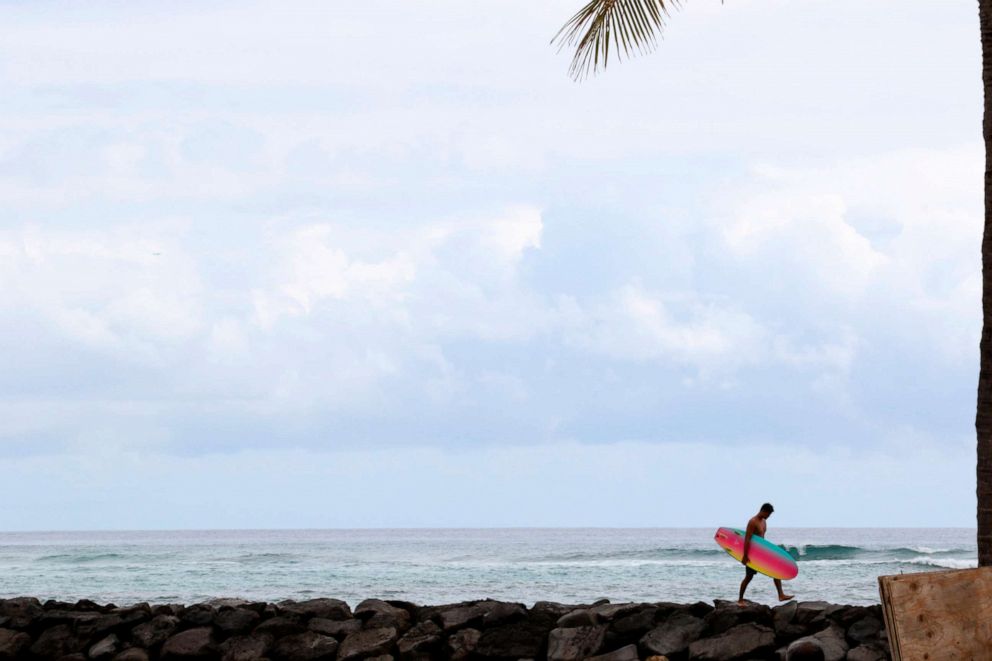 PHOTO: A surfer returns to Waikiki Beach in Honolulu, April 21, 2020. Hawaii has some of the lowest coronavirus infection and mortality rates in the U.S. 