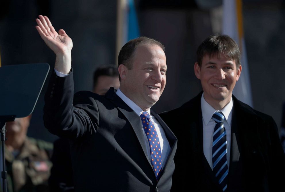PHOTO: FILE - In this Tuesday, Jan. 8, 2019 file photo, Colorado Gov. Jared Polis, left, joins his partner, Marlon Reis, in acknowledging the crowd after Polis took the oath of office during the inauguration ceremony in Denver.   