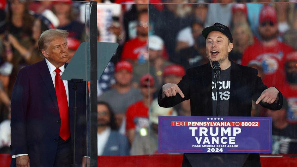 PHOTO: FILE PHOTO: Tesla CEO and X owner Elon Musk speaks as Republican presidential nominee and former president Donald Trump looks on during a rally at the site of the July assassination attempt against Trump, in Butler, Pa., Oct. 5, 2024.