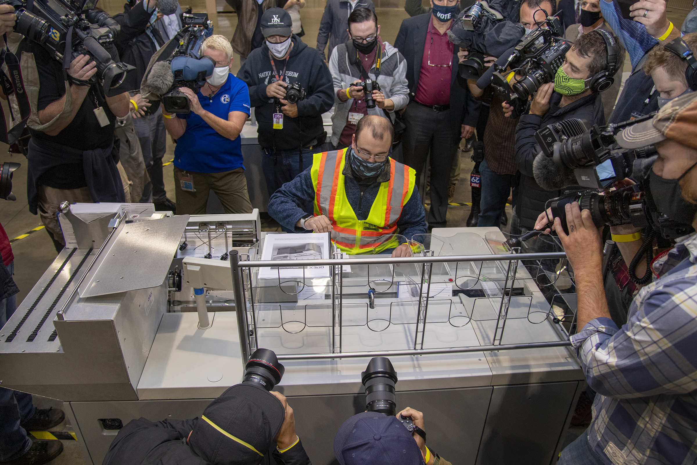 PHOTO: John Hansberry, center, gathers ballots from an extraction machine during a media tour highlighting the preparations for the sorting and counting of mail-in ballots at the Pennsylvania Convention Center, Oct. 26, 2020, in Philadelphia. 