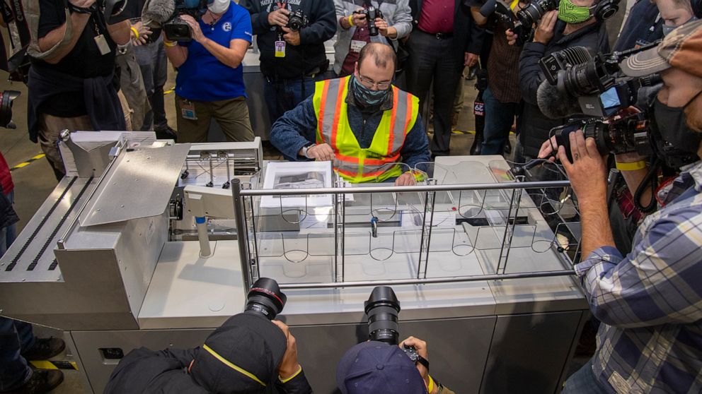 PHOTO: John Hansberry, center, gathers ballots from an extraction machine during a media tour highlighting the preparations for the sorting and counting of mail-in ballots at the Pennsylvania Convention Center, Oct. 26, 2020, in Philadelphia. 