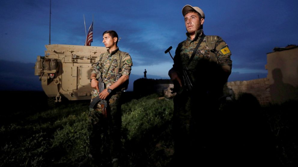 Kurdish fighters from the People's Protection Units (YPG) stand near a U.S military vehicle in the Syrian town of Darbasiya next to the Turkish border, April 28, 2017. 
