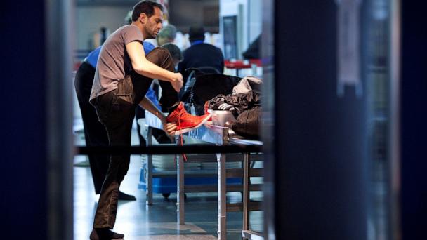 A traveler removes his shoes before going through a security check point at John F. Kennedy Airport in New York, February, 29, 2012.   REUTERS/Andrew Burton/File Photo