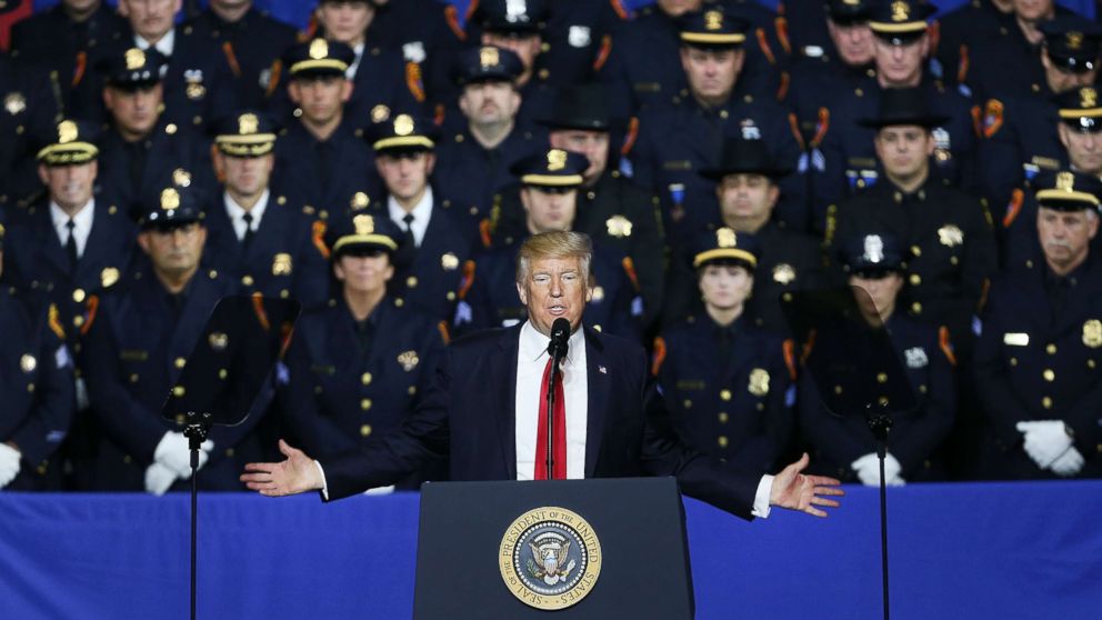 With local and area police officers standing behind him, President Donald Trump speaks at Suffolk Community College on July 28, 2017 in Brentwood, N.Y. where he urged Congress to dedicate more funding to border enforcement and faster deportations.