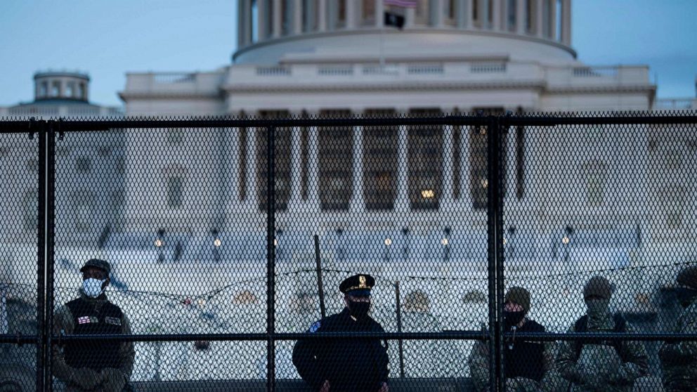 PHOTO: TOPSHOT - A Capitol police officer stands with members of the National Guard behind a crowd control fence surrounding Capitol Hill a day after a pro-Trump mob broke into the US Capitol on Jan. 7, 2021, in Washington, D.C.