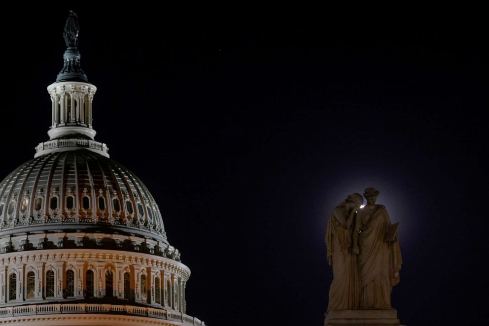 A pink Supermoon provides a halo behind the Peace Monument, with figures representing Grief and History, at the U.S. Capitol on April 26, 2021.  