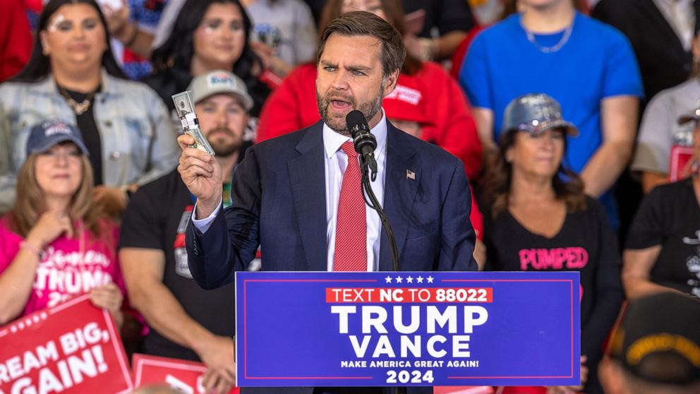 PHOTO: Senator and Republican vice presidential candidate J.D. Vance holds up money while speaking during a campaign rally in Sanford, N.C., Nov. 3, 2024.