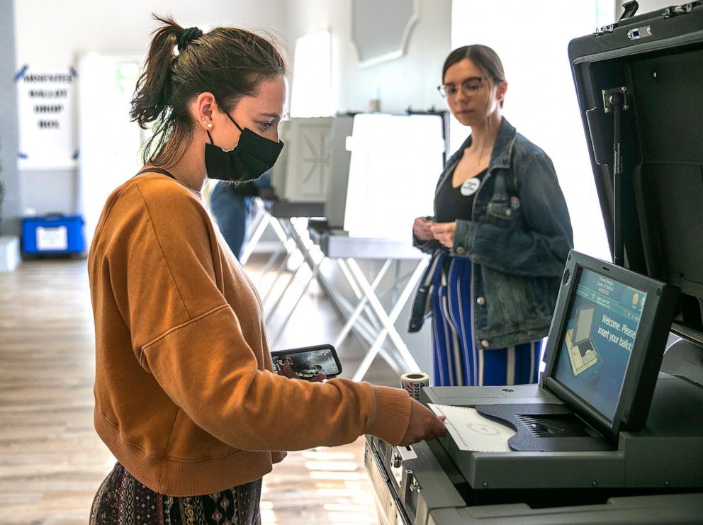Sydney Johnson casts her ballot as election official Clare Lewis watches near Stafford, Virginia on June 8, 2021. It was Johnson's first time voting. 