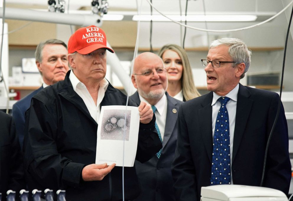 PHOTO: President Donald Trump holds a photograph of coronavirus as Dr. Steve Monroe,right, with CDC speaks to members of the press at the headquarters of the Centers for Disease Control and Prevention in Atlanta on March 6, 2020.