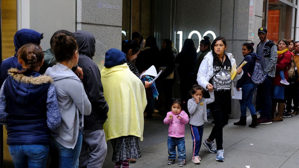 File - In this Jan. 31, 2019, file photo, hundreds of people overflow onto the sidewalk in a line snaking around the block outside a U.S. immigration office with numerous courtrooms in San Francisco. Federal judges are being asked to block a new Trum