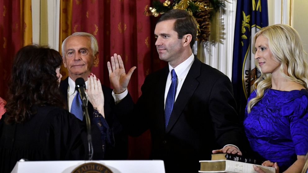 Kentucky Supreme Court Justice Michelle M. Keller, left, gives the oath of office to Andy Beshear to become Kentucky's governor in Frankfort, Ky., early Tuesday, Dec. 10, 2019. Holding the Bible is Beshear's wife, Britainy. (AP Photo/Timothy D. Easle
