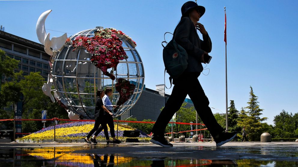 People walk by a globe structure showing the United States of America on display outside a bank in Beijing, Monday, May 6, 2019. U.S. President Donald Trump raised pressure on China on Sunday, threatening to hike tariffs on $200 billion worth of Chin