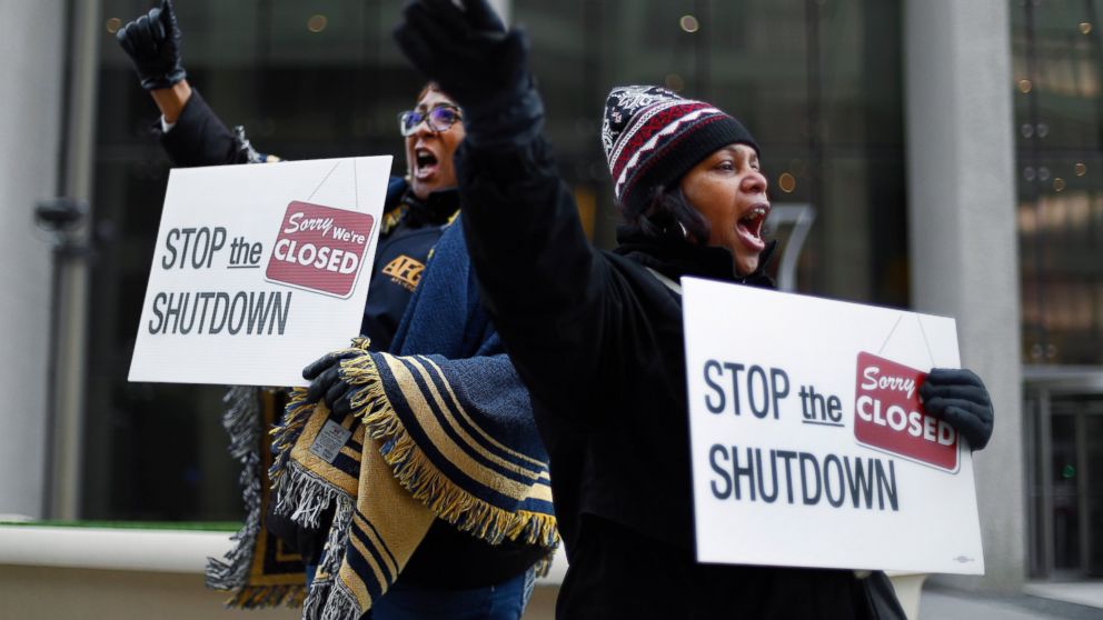 FILE - In this Jan. 10, 2019 file photo Cheryl Monroe, right, a Food and Drug Administration employee, and Bertrice Sanders, a Social Security Administration employee, rally to call for an end to the partial government shutdown in Detroit. The govern