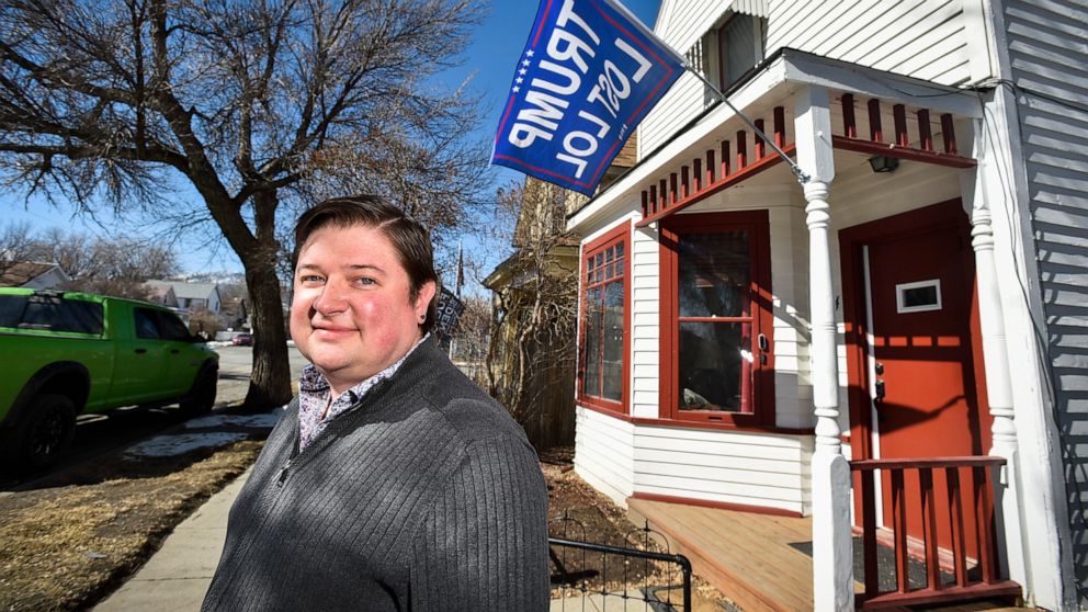 Tim Mielke, 36, poses for a photo outside his Helena, Mont., home on March 10, 2021, where he has a flag hung that says "TRUMP LOST LOL." A Montana man who was cited for disorderly conduct for yelling at his neighbor in a political flag dispute has p