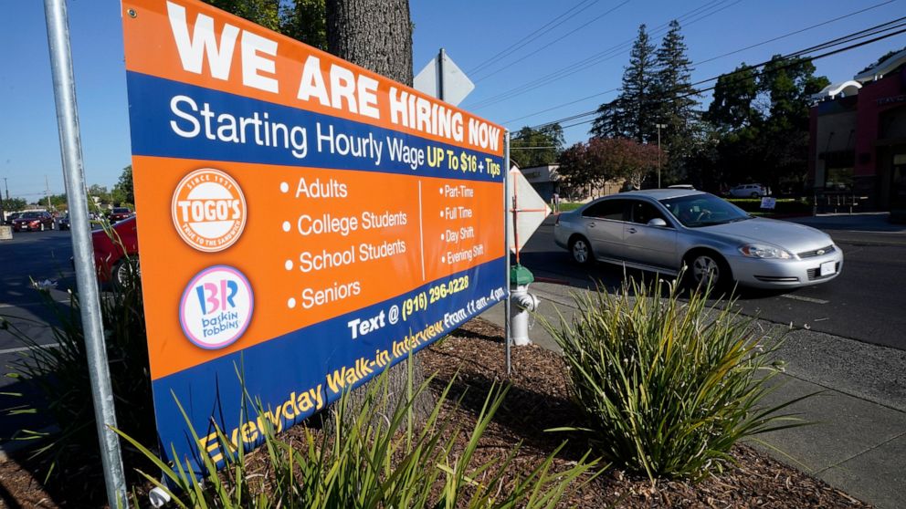 FILE - A car passes a hiring banner in Sacramento, Calif., Friday, July 16, 2021. California's unemployment rate dipped a half-percentage point in December as the most populous state added 50,700 nonfarm jobs, accounting for more than a quarter of th