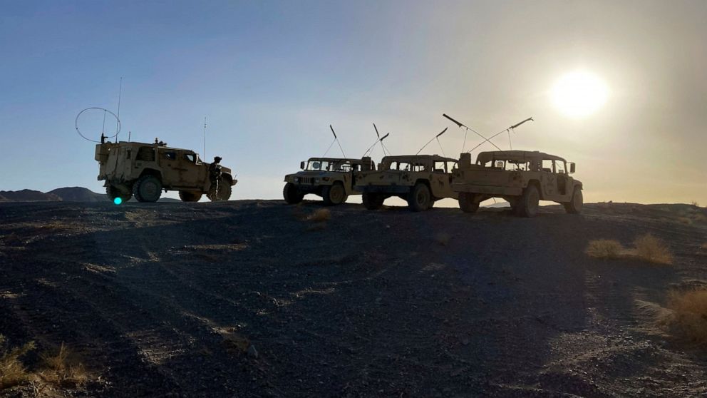 Army vehicles on the ridge, as soldiers from the 2nd Brigade, 1st Cavalry Division, prepare to attack the enemy in the town nearby, during an early morning training exercise at the National Training Center at Fort Irwin, Calif., April 12, 2022. (AP P