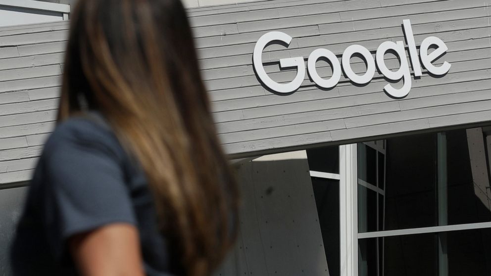 FILE - A woman walks below a Google sign on the campus in Mountain View, Calif., on Sept. 24, 2019. More than 40 Democratic members of Congress are asking Google to stop what they see as the unnecessary collection and retention of peoples' location d