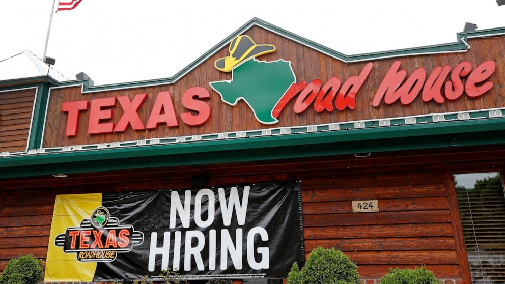 A "Now Hiring" sign Is displayed outside a Texas Roadhouse restaurant, Friday, June 5, 2020, in Methuen, Mass. The U.S. unemployment rate fell to 13.3% in May, and 2.5 million jobs were added — a surprisingly positive reading in the midst of a recess
