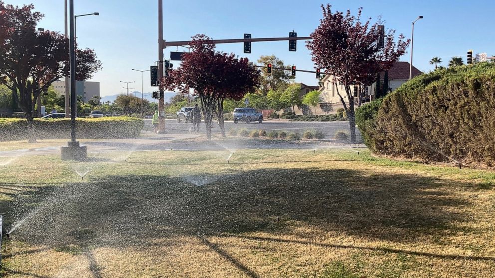 FILE - In this April 9, 2021, file photo, sprinklers water grass near a street corner in the Summerlin neighborhood of northwest Las Vegas. Nevada Gov. Steve Sisolak signed legislation on Friday, June 4 to make the state the first in the nation to ba