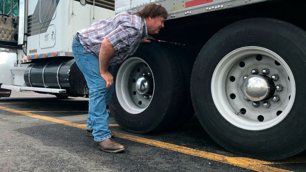 In this June 13, 2019 photo, truck driver Terry Button looks over his trailer during at stop in Opal, Va. The Trump administration has moved a step closer to relaxing federal regulations governing the amount of time truck drivers can spend behind the
