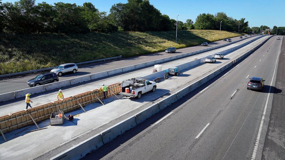 FILE - Traffic flows past workers in a construction zone along Interstate 55 in St. Louis, June 9, 2022. United States transportation officials announced $2.2 billion for local infrastructure projects on Thursday, Aug. 11, 2022, paving the way for ne