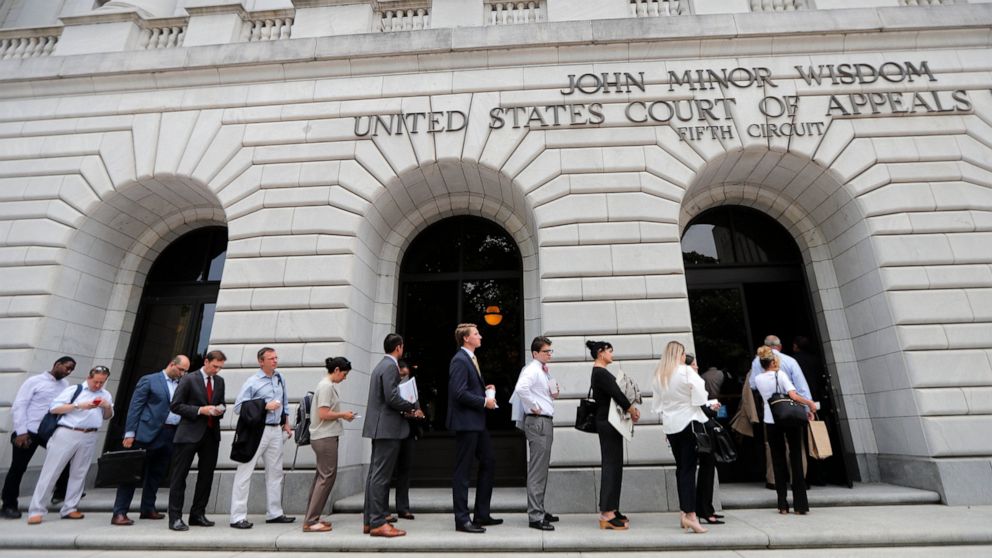 FILE - In this July 9, 2019 file photo, people wait in line to enter the 5th Circuit Court of Appeals in New Orleans. On Wednesday, Feb. 26, 2020, the federal appeals court said the winner-take-all system Texas uses to assign Electoral College presid