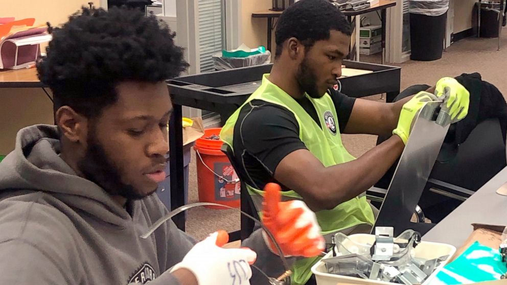 In this Jan. 16, 2020 photo, Nicholas Thomas, left, and Joe Wright, right, prepare school safety signs as part of the AmeriCorps Urban Safety Program at Wayne State University's Center for Urban Studies. Volunteers will post the signs and also help b