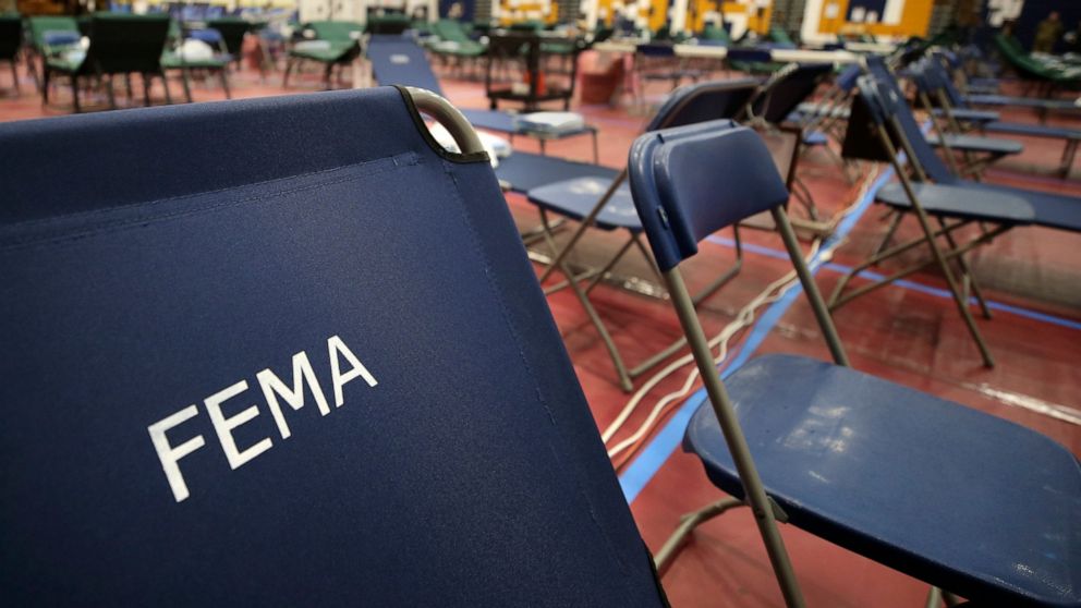 FILE - A portable cot, with the Federal Emergency Management Agency logo FEMA printed on the backrest, and other cots line the basketball court at a makeshift medical facility in a gymnasium at Southern New Hampshire University in Manchester, N.H., M