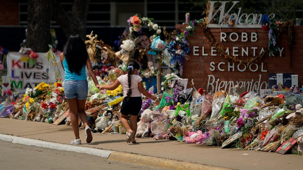 n this July 12, 2022, photo, Visitors walk past a makeshift memorial honoring those killed at Robb Elementary School, in Uvalde, Texas. Parents in Uvalde, Texas, are livid about the security lapses that contributed to the school shooting this spring.